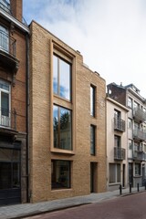 Obraz premium During the daylight hours, the striking modern brick architecture makes a bold statement on a picturesque urban street nestled within a historic neighborhood