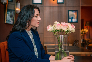 Smiling woman with flowers in a cafe, black and white portrait