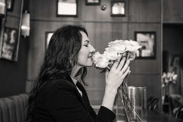Smiling woman with flowers in a cafe, black and white portrait