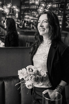 Smiling woman with flowers in a cafe, black and white portrait