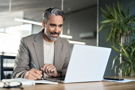 Busy elegant mature business man, middle aged professional ceo executive, serious old businessman investor looking at laptop computer thinking on corporate finances working in office at desk. - Powered by Adobe