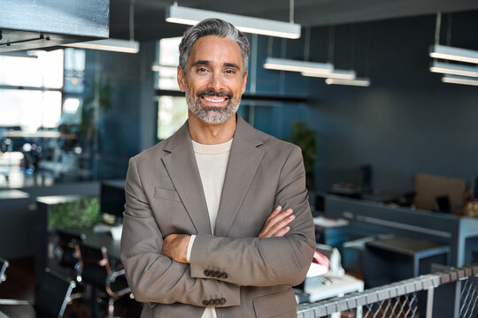 Confident happy mature older professional businessman executive manager, successful lawyer in suit standing arms crossed in office. Smiling middle aged ceo business man looking at camera, portrait.