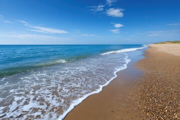 Serene coastal vista with gentle waves rolling onto a sandy shore under a bright blue sky