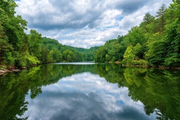 Serene woodland lake reflecting dramatic cloudy skies and lush green forested shores
