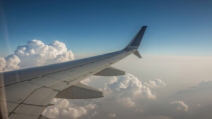 Obraz premium The wing of an airplane stretches through the soft clouds, capturing a breathtaking moment above the earth, where sky and metal meet in a serene and dreamy high-altitude view