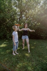Fototapeta premium A mother and her son with hearing aids launch a paper airplane in a park, a heartwarming moment of inclusive play and bonding in nature. Perfect for disability awareness and family lifestyle content
