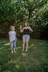 Fototapeta premium A mother and her son with hearing aids launch a paper airplane in a park, a heartwarming moment of inclusive play and bonding in nature. Perfect for disability awareness and family lifestyle content