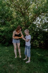 A mother and her son with hearing aids launch a paper airplane in a park, a heartwarming moment of inclusive play and bonding in nature. Perfect for disability awareness and family lifestyle content