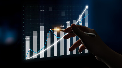 A hand is pointing at a digital chart representing financial growth. The glowing lines and upward bars symbolize positive trends and successful analysis. Impute