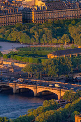 Naklejka premium Aerial view of the Pont Alexandre III over the Seine River, the Parisian riverside and the Tuileries Garden illuminated by sunset light during golden hour, Paris, France.
