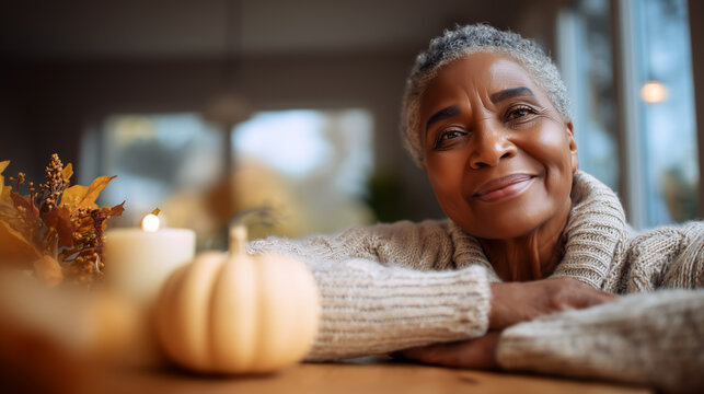 Thanksgiving gratitude concept with peaceful senior woman in cozy sweater. Warm candlelit atmosphere, autumn celebration, holiday contentment. Mature lifestyle, happiness, seasonal tradition.