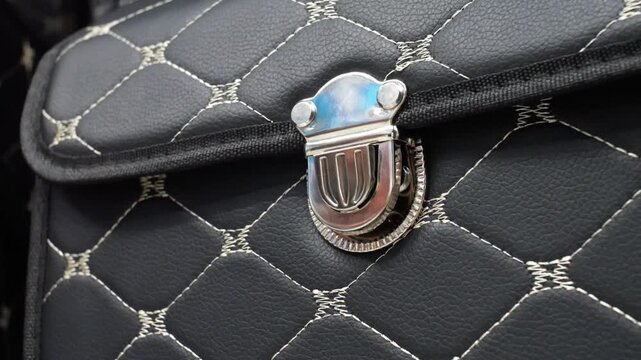 Close-up of male hands closing a black leather suitcase with a snap button
