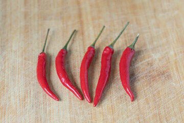five bright red chili peppers on a neutral background