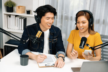Smiling radio influencer hosts wearing headphones with channel social media online live streaming...