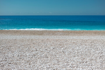 Crystal clear turquoise water meets smooth pebble beach on Greek island coastline, perfect Mediterranean summer destination