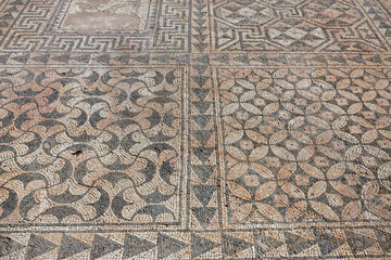 Intricate ancient Roman mosaic floor with geometric wave patterns and decorative borders displaying masterful craftsmanship