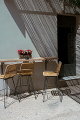 Stylish wicker chairs on Mediterranean terrace create striking shadow patterns from overhead bamboo screening
