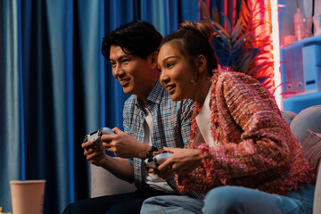 Sitting sofa of happy smiling couple playing video game control by joystick fronted snack and...