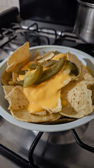 Vertical photo of a plate of nachos with melted yellow cheese.