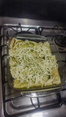 Vertical photo of delicious green chicken enchiladas with cheese.