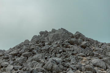 Massive limestone rock formation against overcast sky creating dramatic mountain summit scene