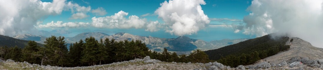 Wide panoramic view of mountain ranges with blue sky white clouds and limestone terrain
