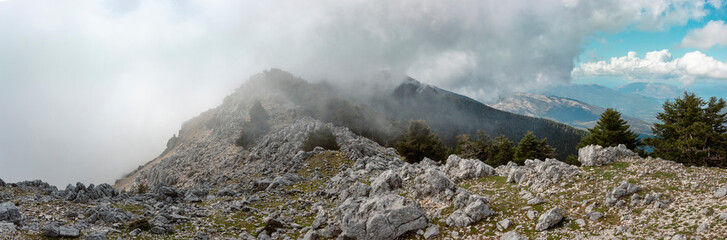 Expansive panoramic mountain landscape with limestone formations and atmospheric clouds