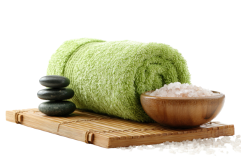 Rolled light green towel, spa stones, and bowl of bath salt on a bamboo mat