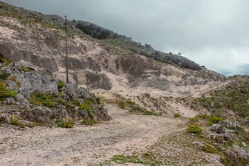 Rural mountain road with electrical infrastructure winding through Kefalonia's hilly landscape.