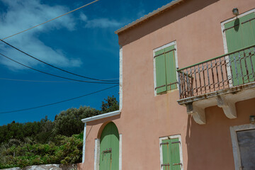 Traditional pink house with mint green shutters showcasing typical Greek island architecture.