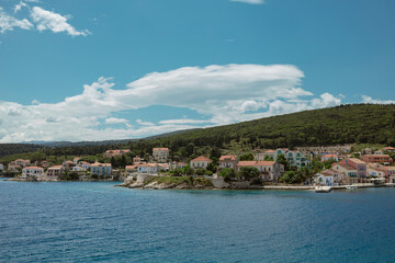 Fototapeta premium Traditional Greek village with colorful houses nestled on hillside overlooking blue Mediterranean.