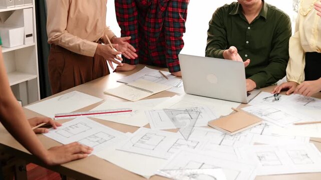 Architect and safety engineer celebrate success design building blueprint project on laptop on table with architectural document and wooden block scatter around at modern office. Closeup. Delineation.