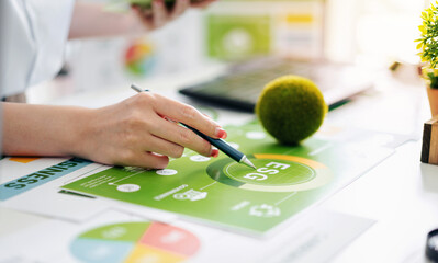 hand analyzing environmental social governance report data charts. Focus on sustainable business...