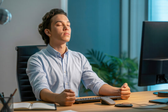 Calm professional taking relaxing mindfulness break from work at his computer to recharge energy