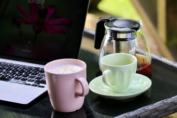 Kubki i komputer na stole - praca w domu. Praca i biznesowy klimat. Zdalna praca.
