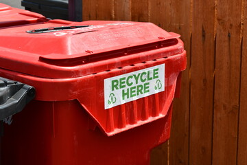 Red recycling bin at large event. Sign says Recycle here.