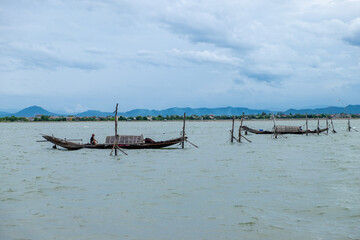 Colorful traditional Vietnamese fishing boats anchored near a beach with large coastal rocks in the background.