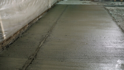 Workers pouring and finishing concrete slab for new industrial floor