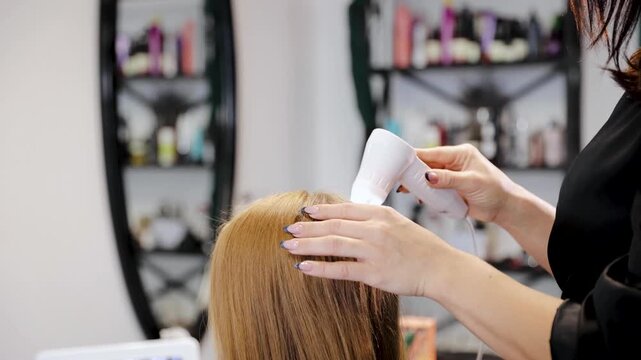 Hairdresser examining client's hair and scalp using special equipment trichoscope in a salon for treatment