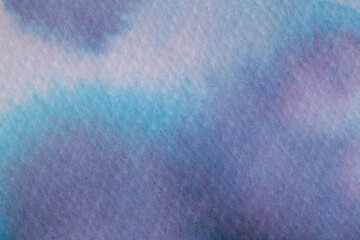 Fluid ink patterns in soft hues create an artistic background on textured paper surface