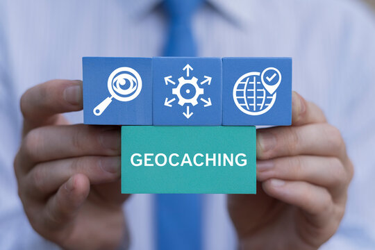 Geocaching International Navigation Treasure Search Game Concept. Person holding blocks with icons sees text: GEOCACHING.
