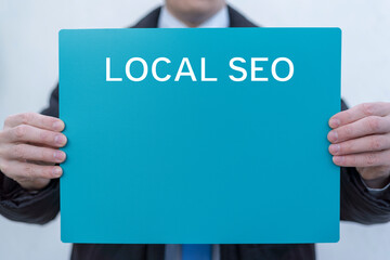 Person holding turquoise banner with inscription: LOCAL SEO. Local search marketing e-commerce. Local seo strategy, local search optimization template concept.