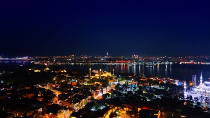 Light of the night city reflects in the dark waterscape. Aerial view of Istanbul, Turkey. Fantastically illuminated mosques in the cityscape. - Powered by Adobe
