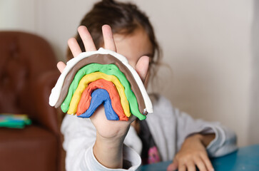 A young girl showing a rainbow she made with colorful modeling dough. 