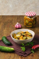 Pickled vegetable salad of cucumbers and carrots in a ceramic bowl on a wooden background. Canning, preparations. Step-by-step recipes.