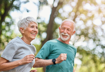 Smiling active mature senior couple jogging together in the park
