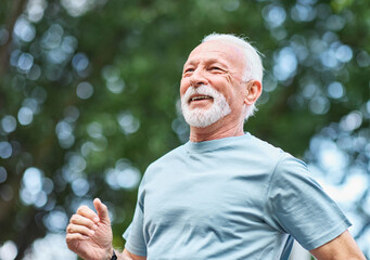 Smiling active mature elderly man jogging running in the park
