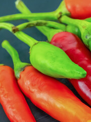 green and red chili peppers lie on a black background, small