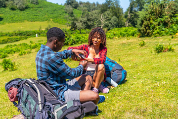 Hikers resting on grassy hillside sharing refreshments during sunny day hike