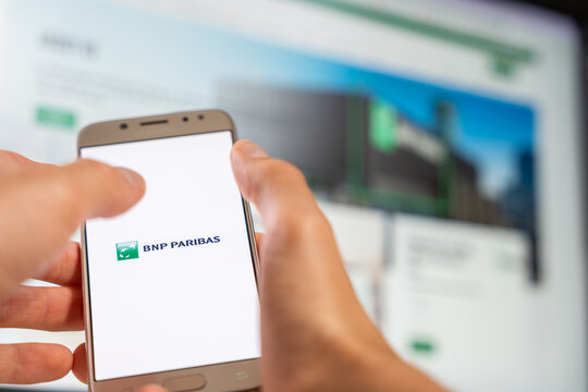 Close up of BNP Paribas logo on smartphone with blurred banking website in background for financial services